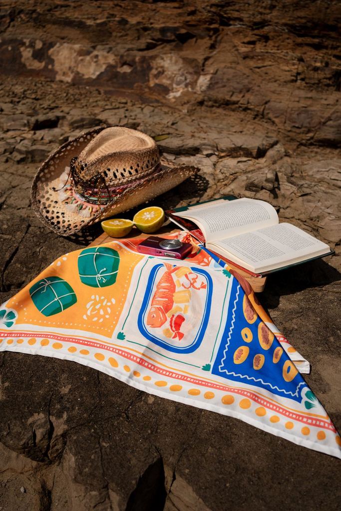 Pañuelo de Clase Luna con sombrero, libro y naranjas sobre una roca: fotografía de producto profesional